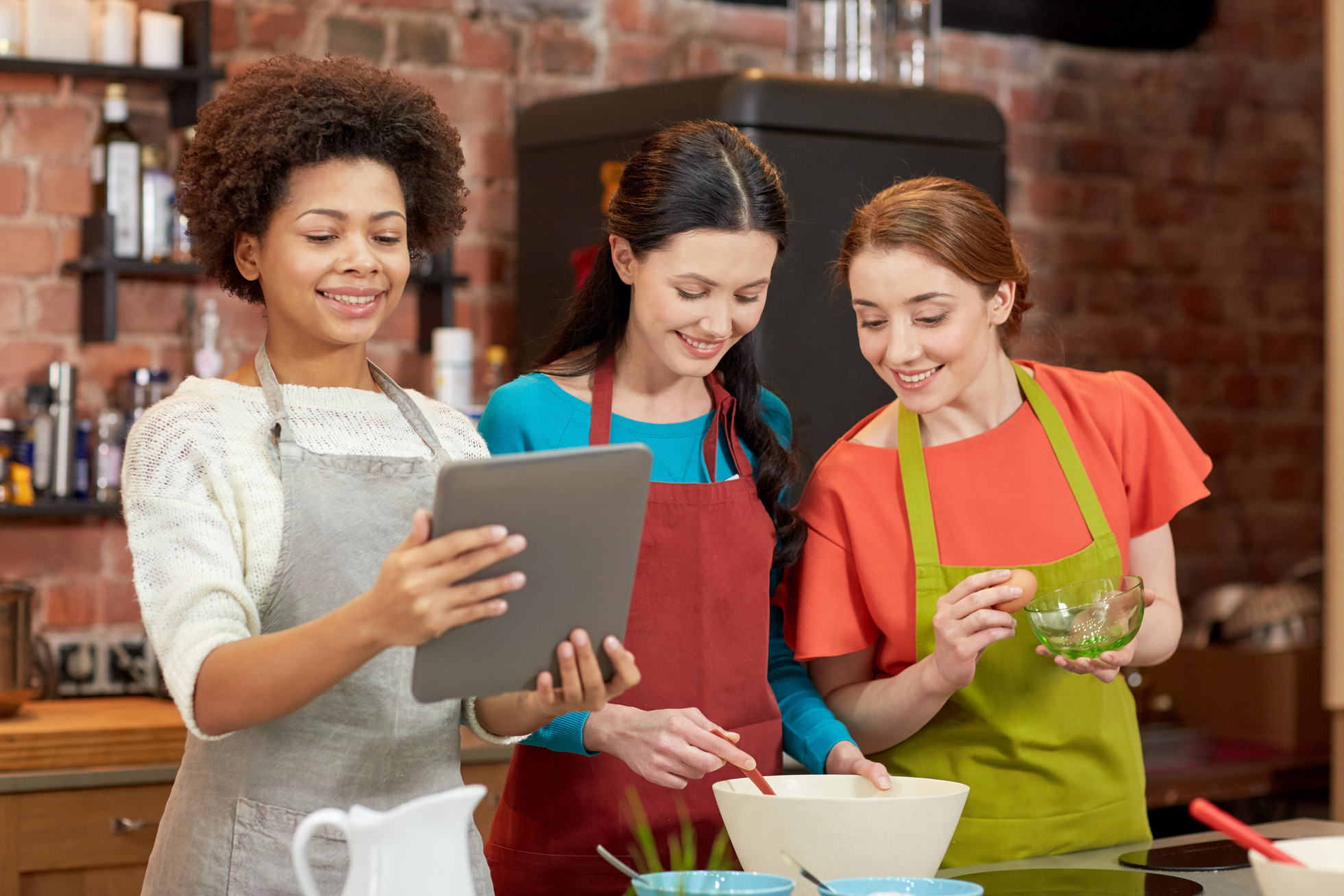 Happy Women with Tablet Pc Cooking in Kitchen